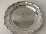 silver plate with scalloped edge on a white surface