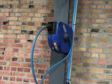 a blue hose attached to a pole next to a brick wall