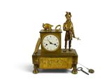 a gold clock with a man standing next to it