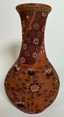 un vase marron orné de fleurs, posé sur un fond blanc