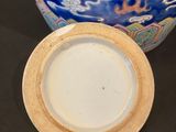 a blue vase and a white plate sitting on a table