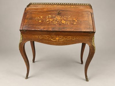 un bureau ancien orné d'un motif floral sur le plateau