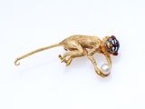 un gros plan sur une broche en forme de singe tenant une perle dans la bouche