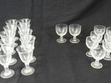 six verres à vin transparents sont alignés sur un fond noir
