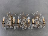 two brass and crystal sconces mounted on a wall