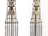 two pairs of earrings with chains hanging from them on a white surface