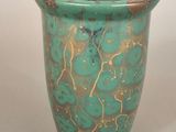 un vase vert orné de motifs dorés et bleus