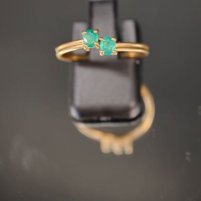 un gros plan d'une bague en or sertie de deux émeraudes