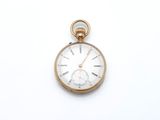 a gold pocket watch with a white face on a white surface
