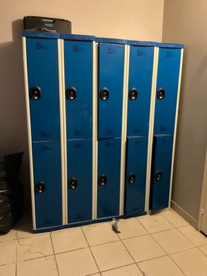 several blue lockers are lined up in a room with a trash can