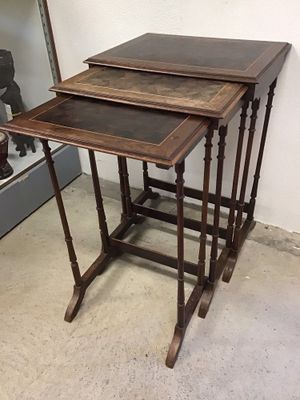 Dans une pièce, trois tables en bois sont empilées les unes sur les autres.