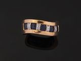 a gold ring with sapphires and diamonds on a black surface
