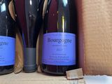 three bottles of wine sit in a cardboard box on a table