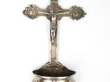 une croix en argent posée sur un bol en argent, le tout sur un fond blanc