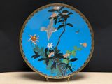 une assiette bleue ornée d'un oiseau et de fleurs
