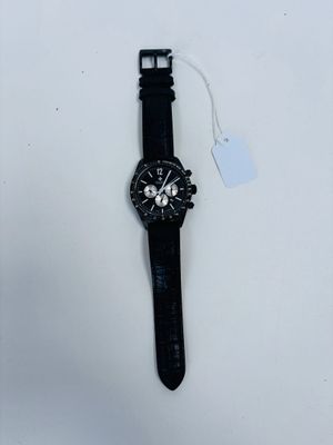 the watch is laying on a white surface next to a tag