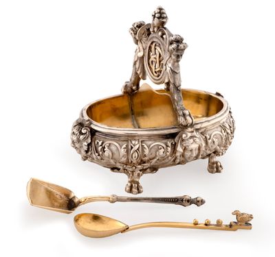 un plateau ancien en argent avec une cuillère et un repose-cuillère posés sur une surface blanche