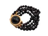 un gros plan sur un bracelet en perles noires muni d'un fermoir doré