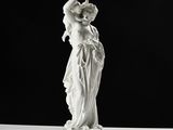 une statue représentant une femme tenant un bébé dans ses bras, posée sur un socle
