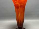 orange and brown glass vase sitting on top of a wooden stand