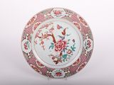 a plate with flowers and birds on it on a stand