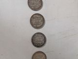 four coins are arranged in a row on a white surface