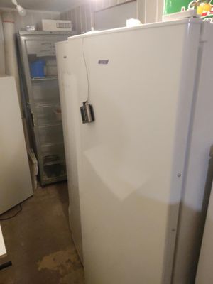 Plusieurs réfrigérateurs blancs sont alignés dans une pièce sans portes