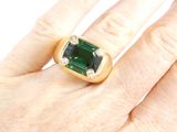 an image of a person ' s hand with a ring with a green stone