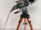 un appareil photo posé sur un trépied, sur une surface blanche