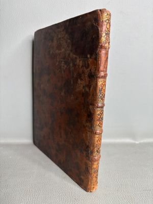 un vieux livre à la couverture brune posé sur une surface blanche