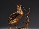 a bronze sculpture of a bird on a branch with flowers