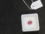 a pink stone in a square container next to a tag