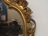 a gold mirror on the wall next to a bench