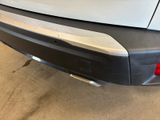 the rear end of a white car with a black bumper