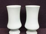 deux vases blancs posés l'un à côté de l'autre sur une table