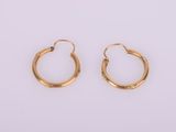 une paire de boucles d'oreilles en or sur fond blanc