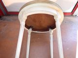 a white table with a round top on a brown floor