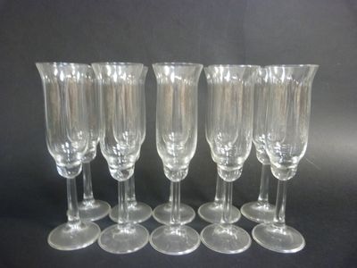 six clear wine glasses are lined up on a black surface