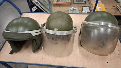 three helmets sitting on top of a wooden table in a room