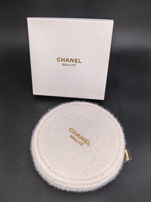 une montre Chanel dans un coffret blanc posé sur une surface noire
