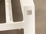a close up of a white bench with a metal frame