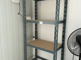 a small room with a fan and shelves in it