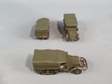 three toy army vehicles sitting on a white surface