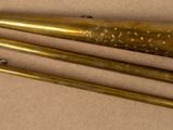 three brass baseball bats sitting on top of a brown surface