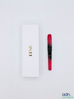 un stylo rouge posé à côté d'une boîte blanche sur une table