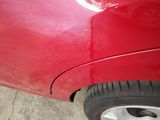 a close up of a red car that has been dented