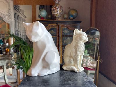 two statues of cats sitting on a table in a living room