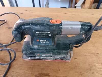 une ponceuse électrique Black & Decker posée sur une table en bois