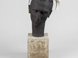 sculpture représentant une tête d'homme avec des cornes, posée sur un bloc