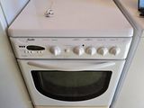 un ordinateur portable posé sur une cuisinière, à côté d'une machine à laver